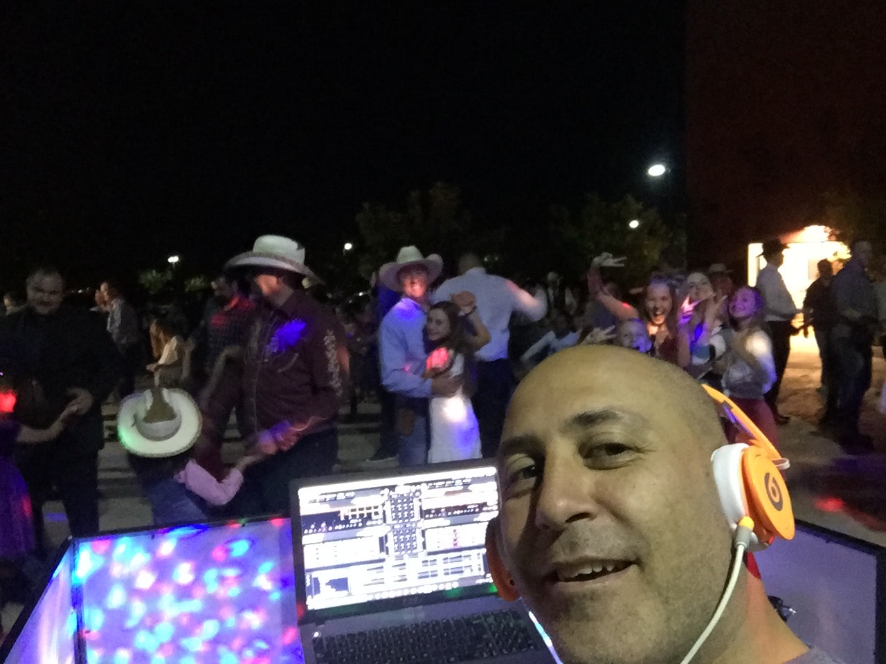 DJ at mixing console with crowd behind